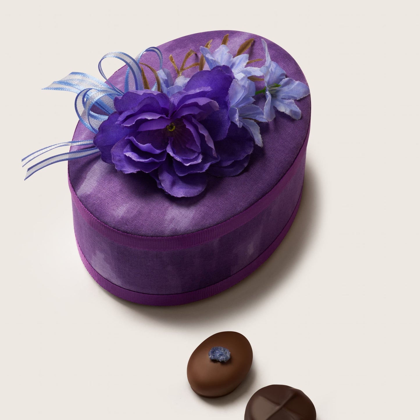 Heart-shaped purple gift box with floral decorations on a light beige background
