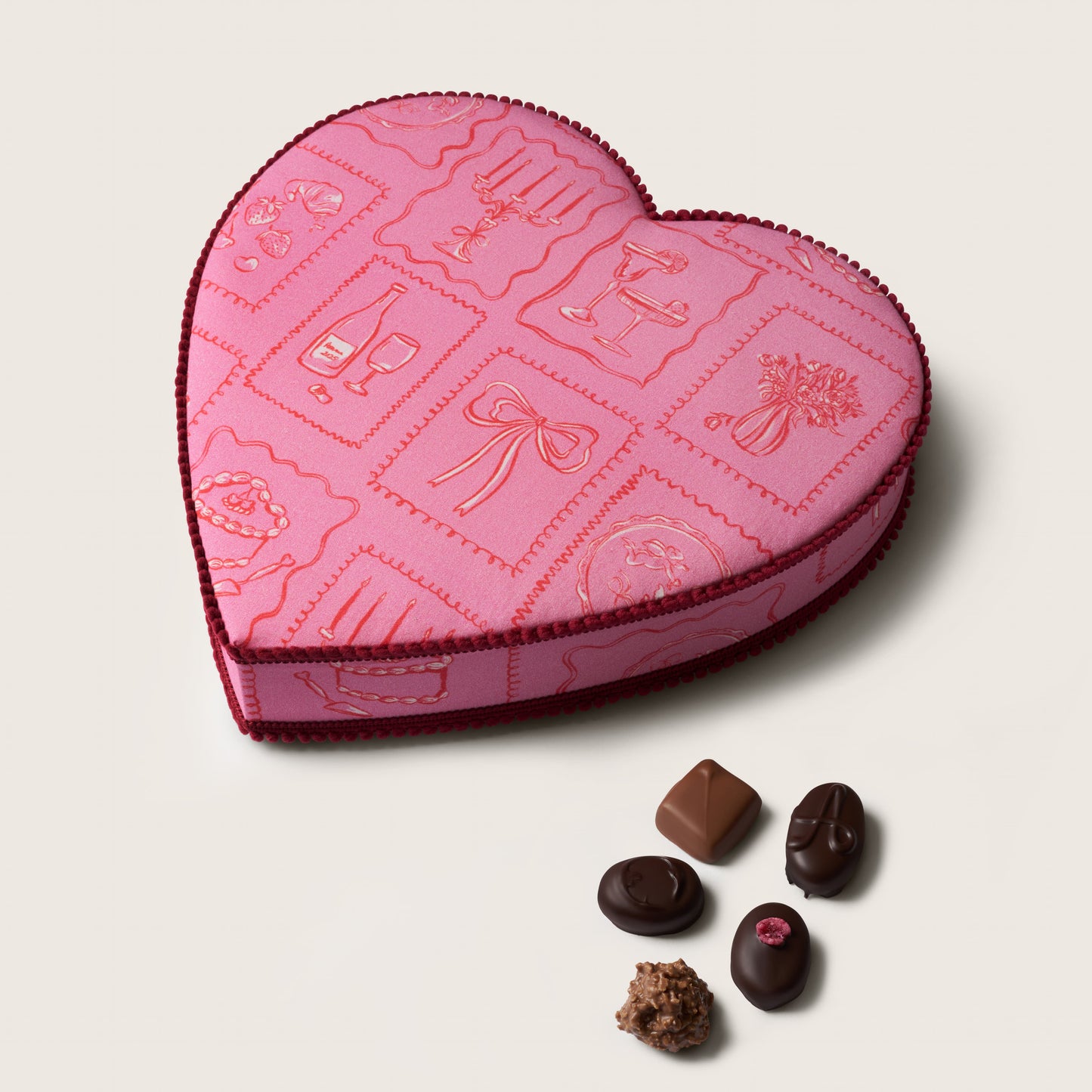 Heart-shaped pink chocolate box with embossed designs on a light gray background