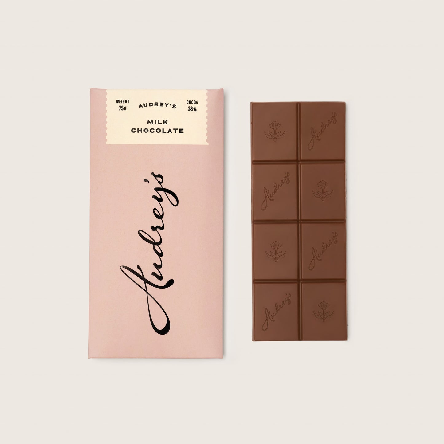 Audrey's chocolate bar packaging and chocolate bars on a light pink background