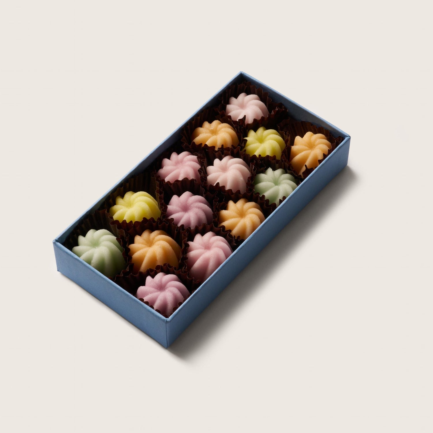 Blue tray of crystallised fondants in a variety of colours on a white background