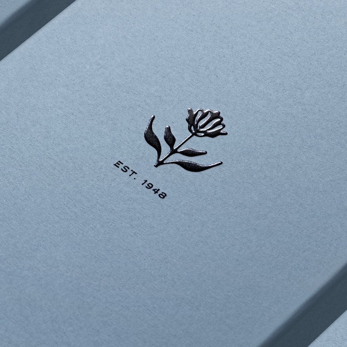 Blue notebook with a black floral design and 'EST. 1948' text on a matching blue background