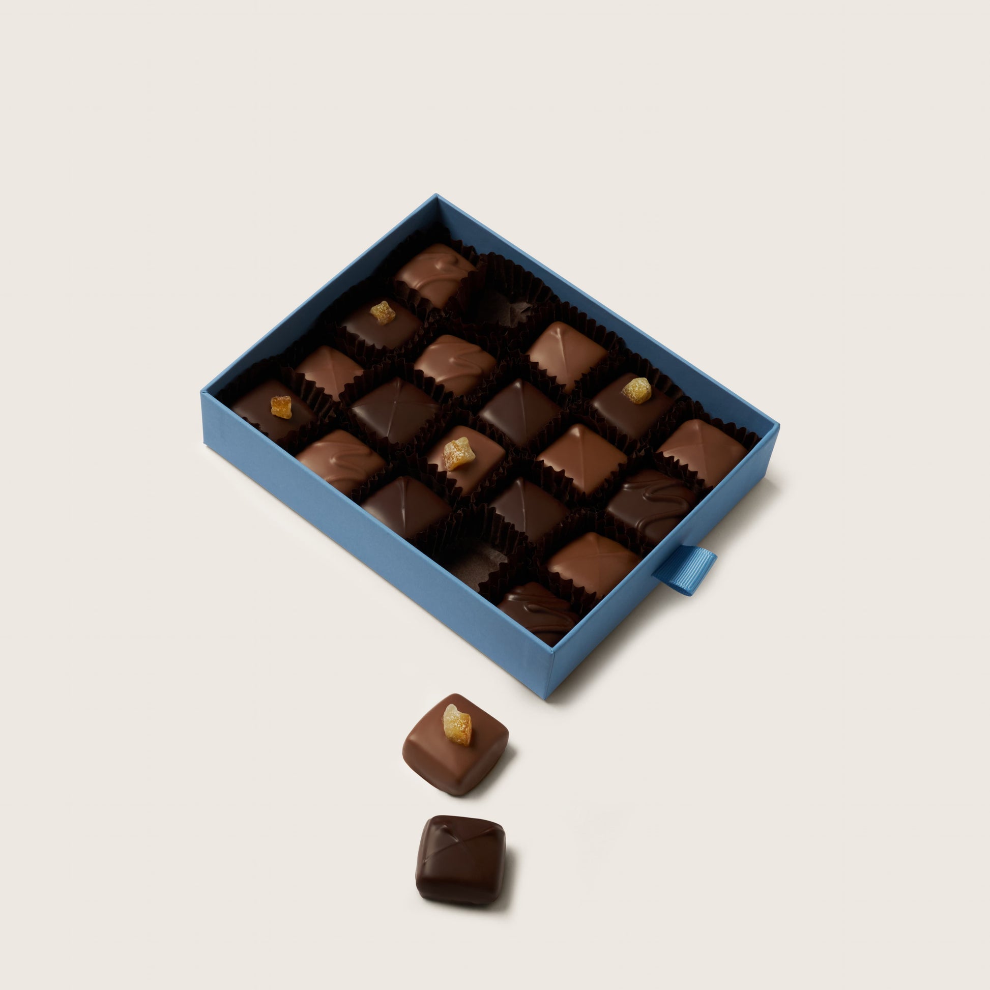 Box of chocolates with a few outside on a light background