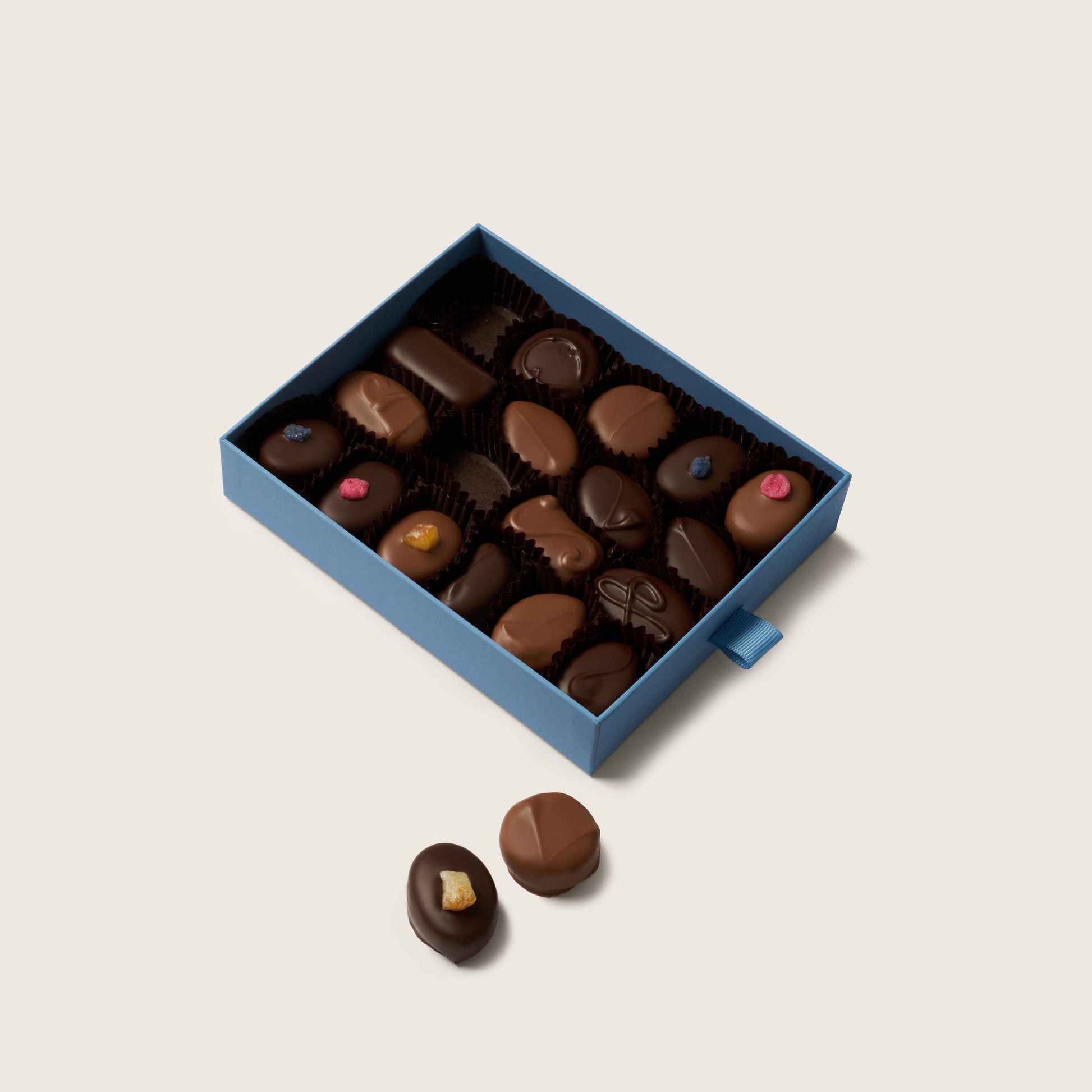 Box of assorted chocolates on a light beige background