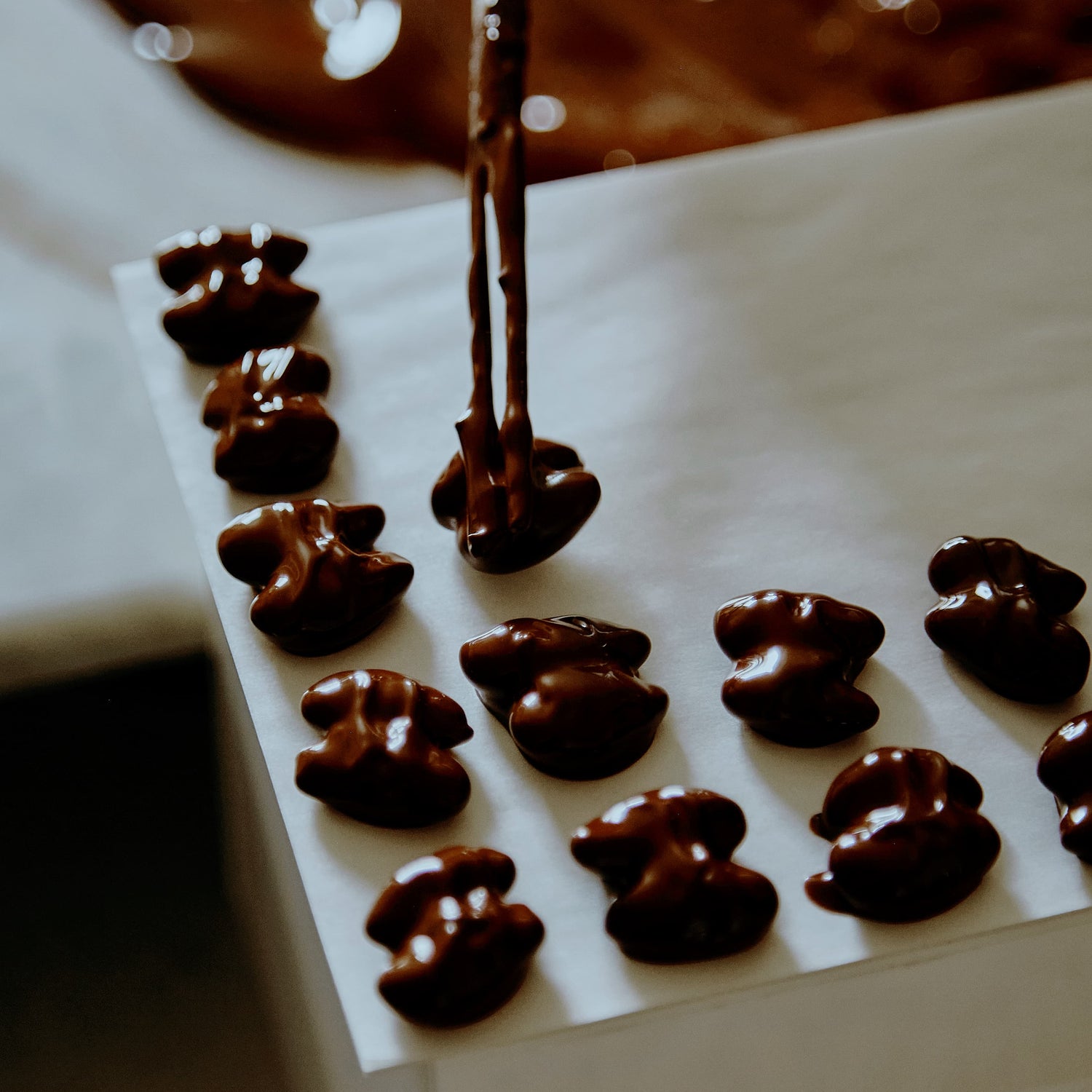 Chocolate truffles being coated with chocolate on a white paper