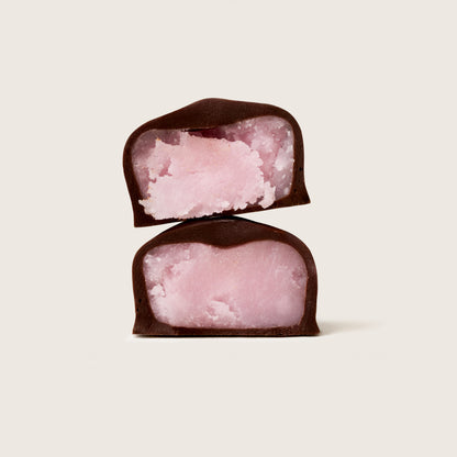 Two pink treats in dark chocolate on a light beige background