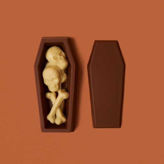 Chocolate coffin with skull and bones on a brown background