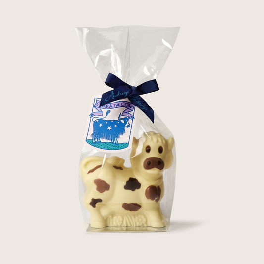 Cow-shaped chocolate in a clear bag with a blue ribbon and label on a white background