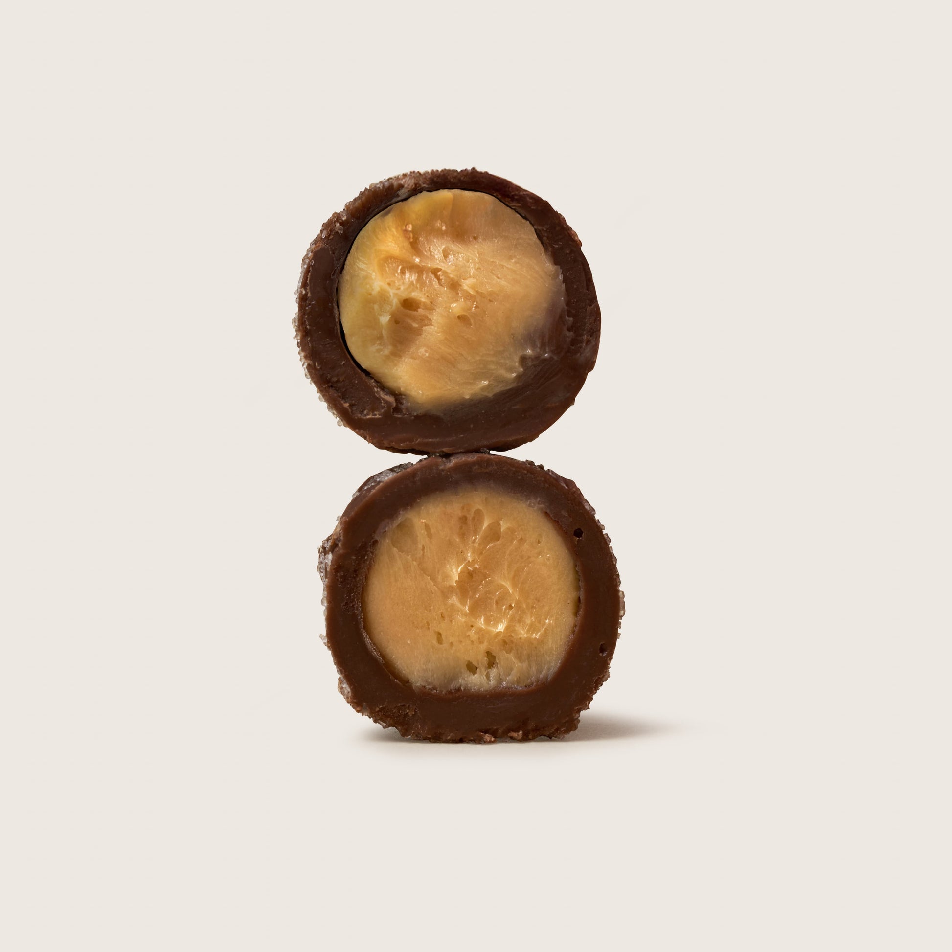 Two chocolate-covered treats stacked on a light beige background