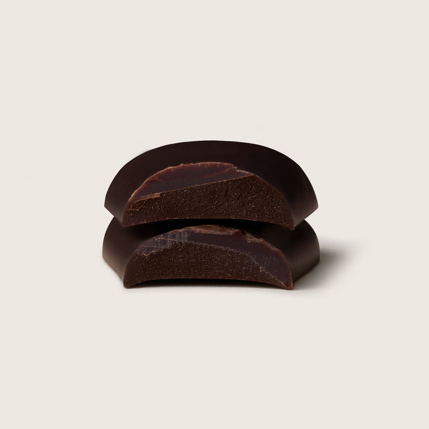Three dark chocolate pieces on a light beige background