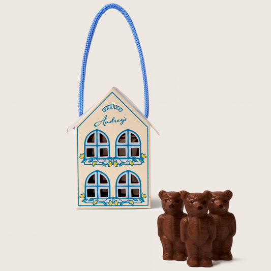 Decorative house with a blue ribbon and two chocolate bears on a white background