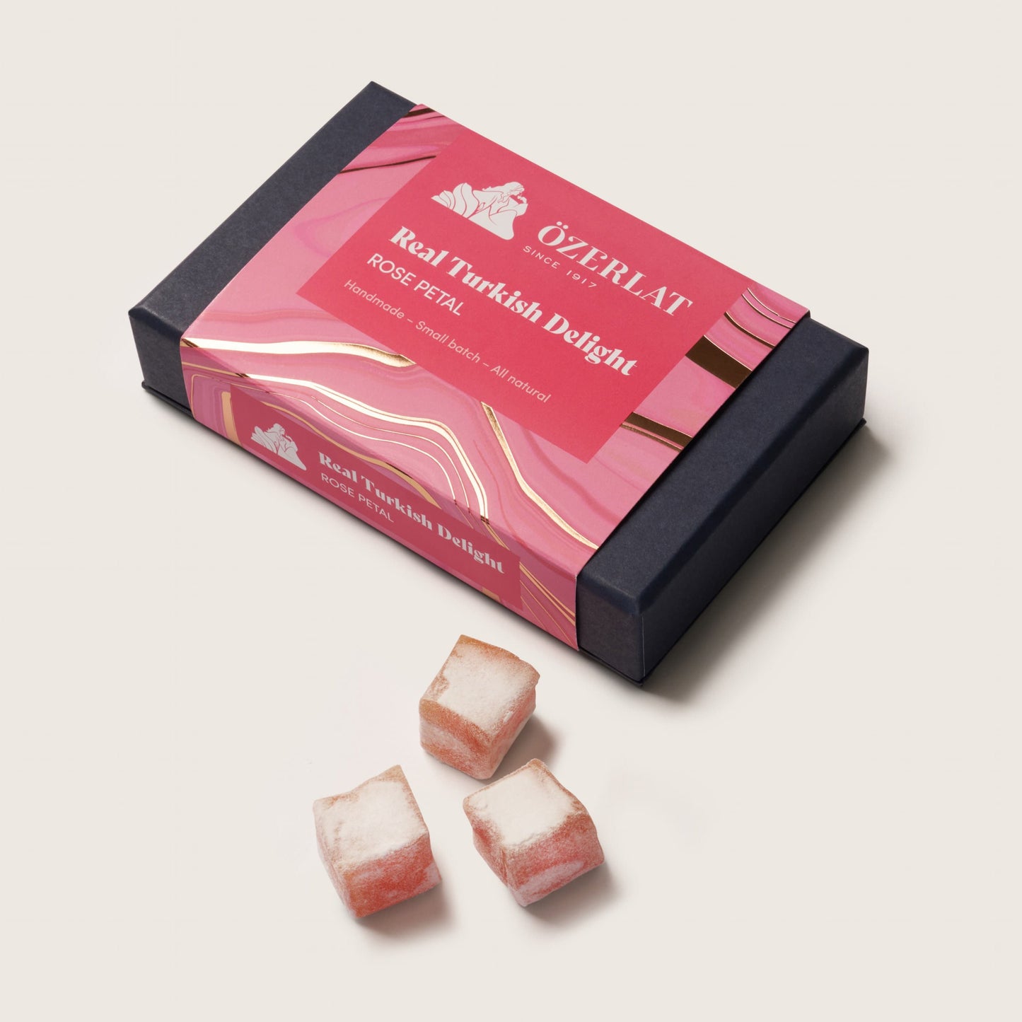Box of Turkish delight with three pieces on a light pink background