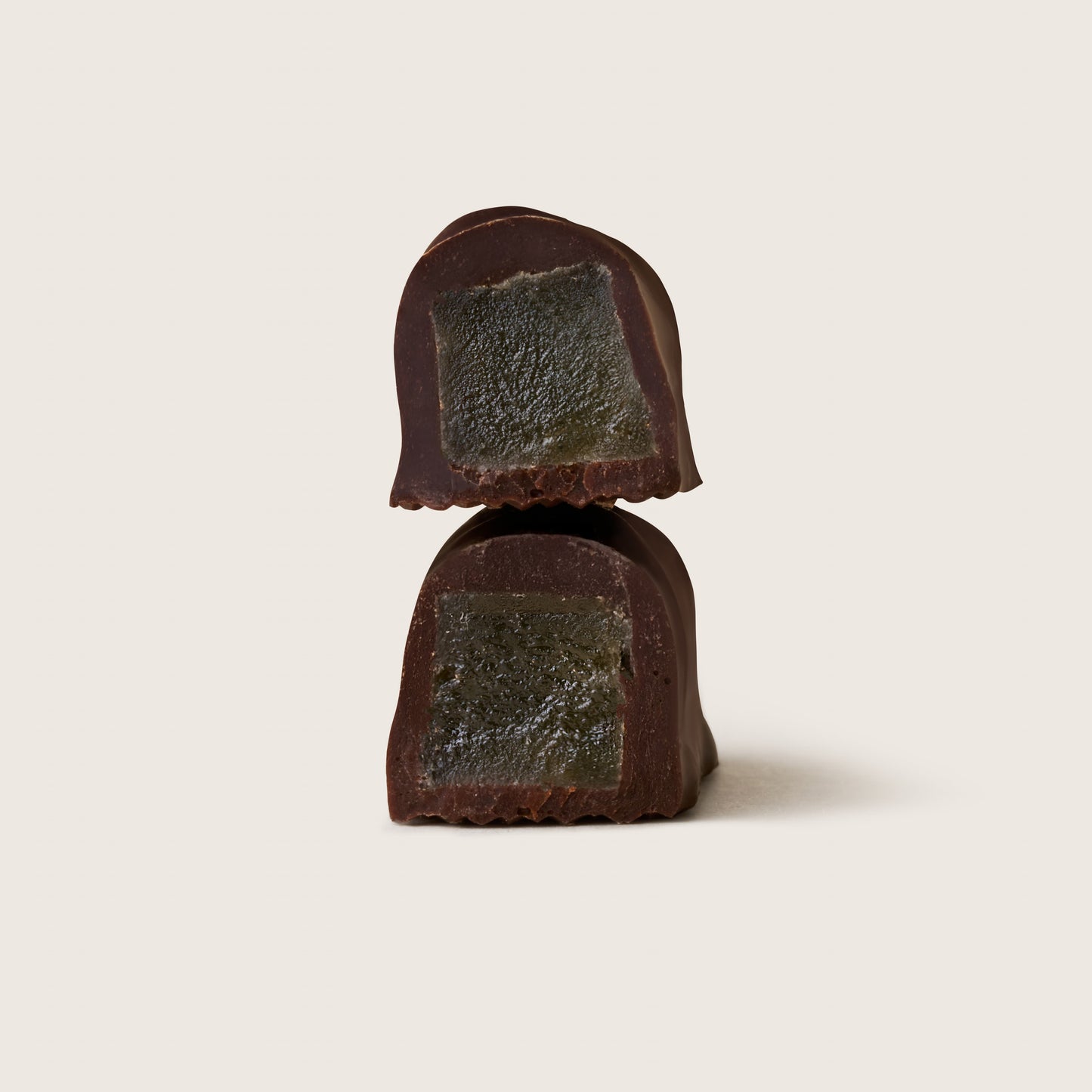 Dark chocolate truffle with a greenish center on a light beige background