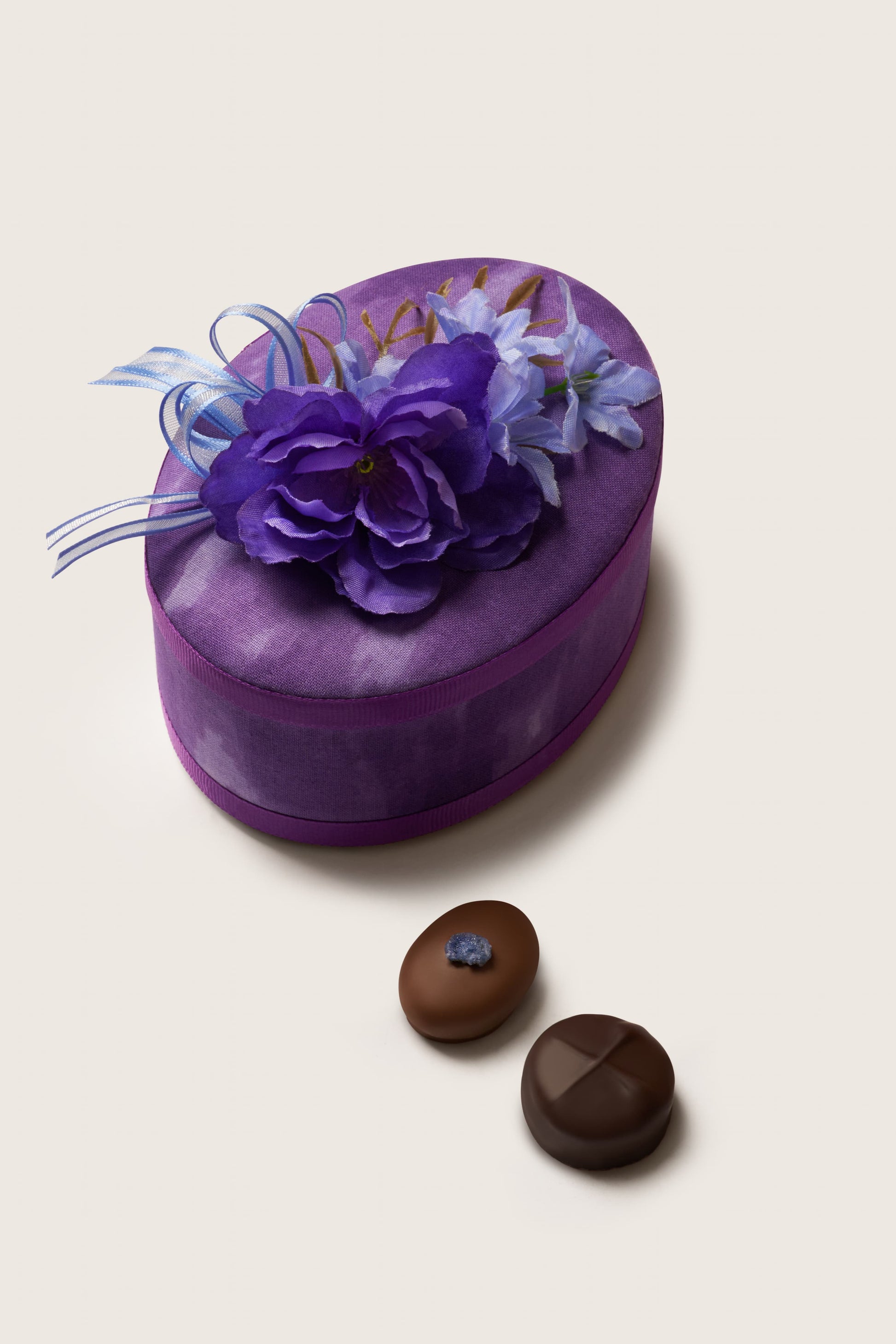 Heart-shaped purple gift box with floral decorations on a light beige background