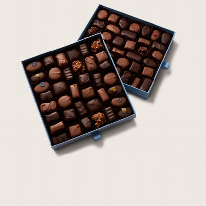 Two boxes of assorted chocolates on a light beige background
