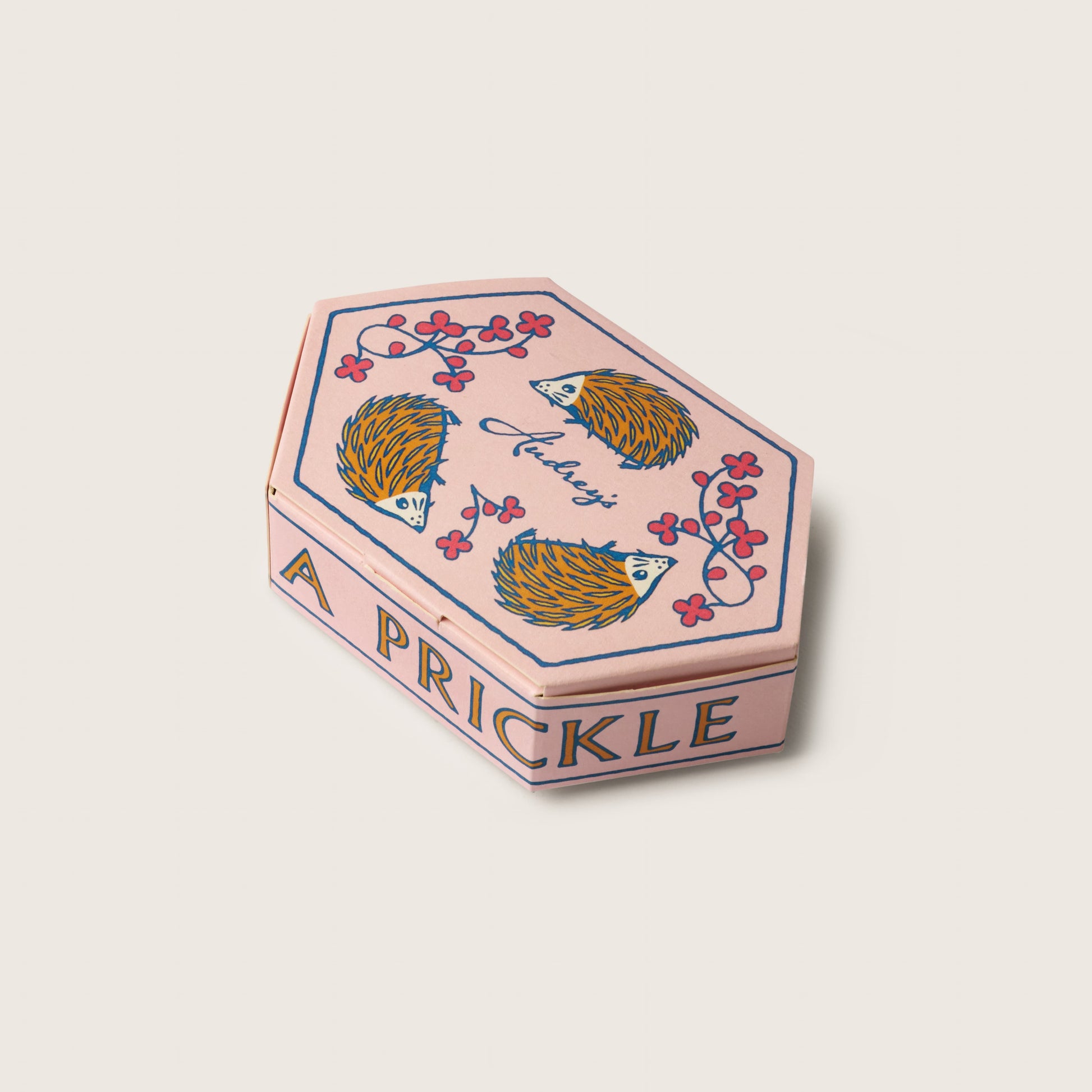 Hexagonal pink box with hedgehog design and 'A Prickle' text on a light beige background