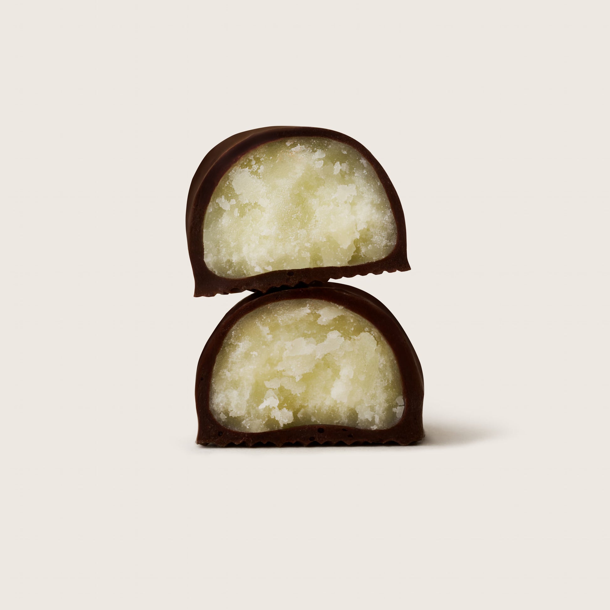 Two chocolate-covered treats with a creamy center on a light beige background