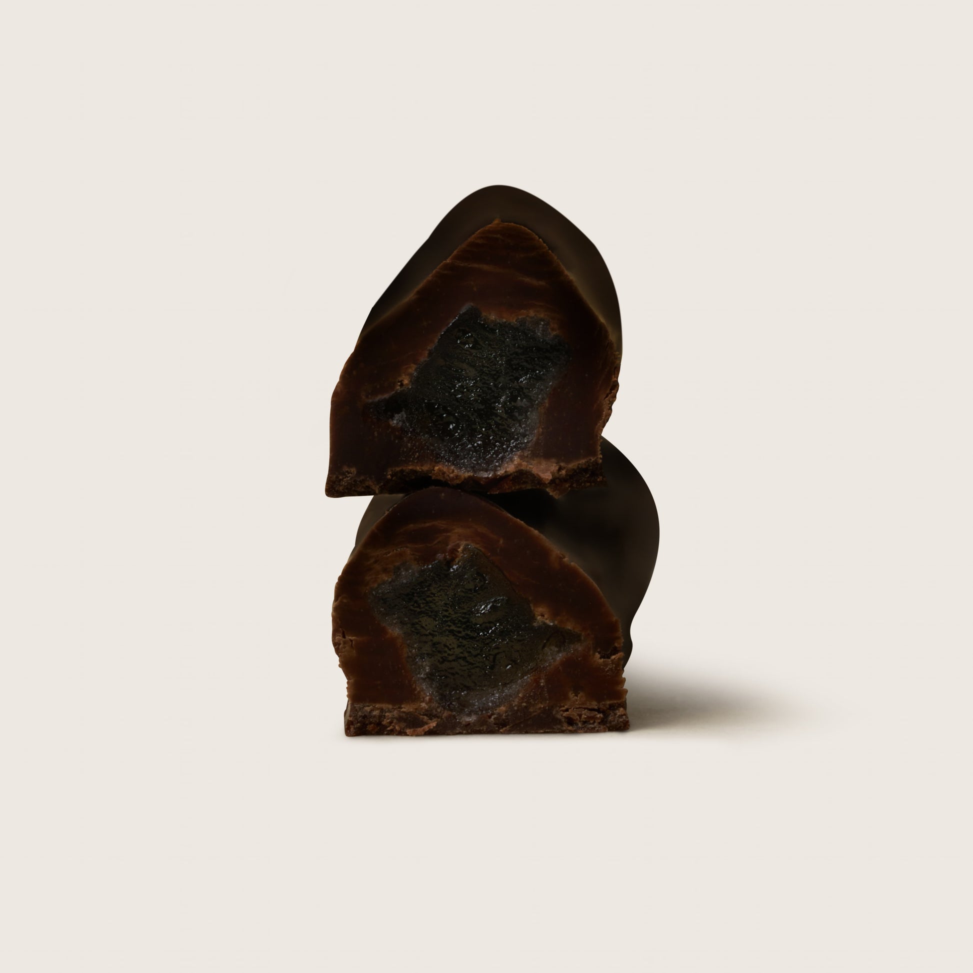 Two pieces of dark chocolate on a light beige background