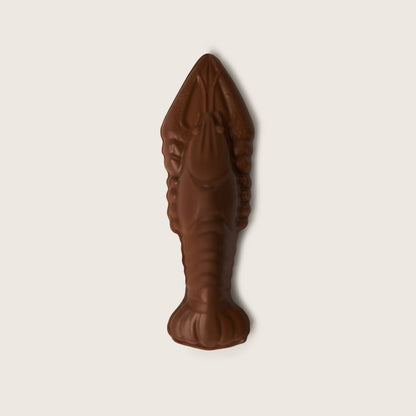 Brown chocolate candy shaped like a lobster on a light beige background