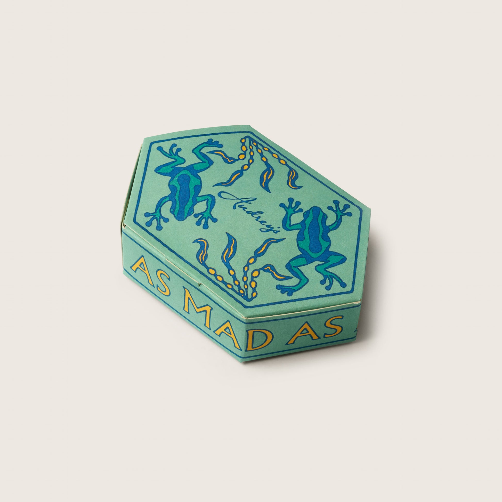 Hexagonal green box with blue frog design and text on a beige background