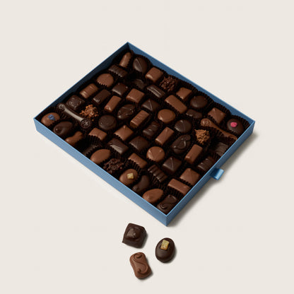 Box of assorted chocolates on a light beige background