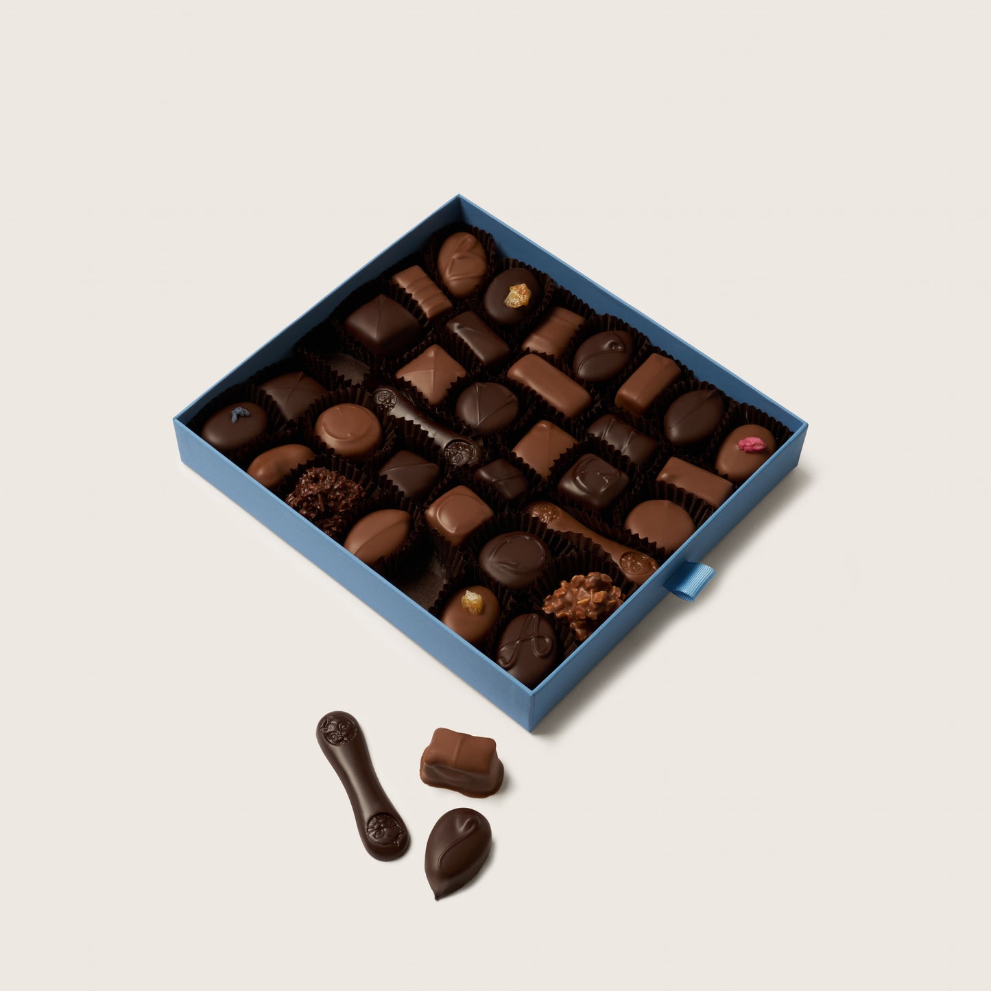 Box of assorted chocolates on a light beige background