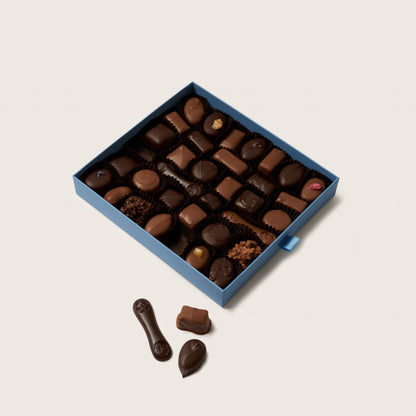 Box of assorted chocolates on a light beige background