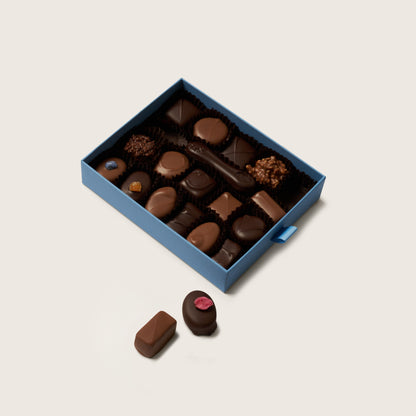 Open box of assorted chocolates on a light beige background