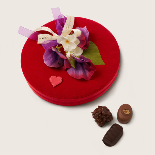Red gift box with floral decoration and chocolates on a white background