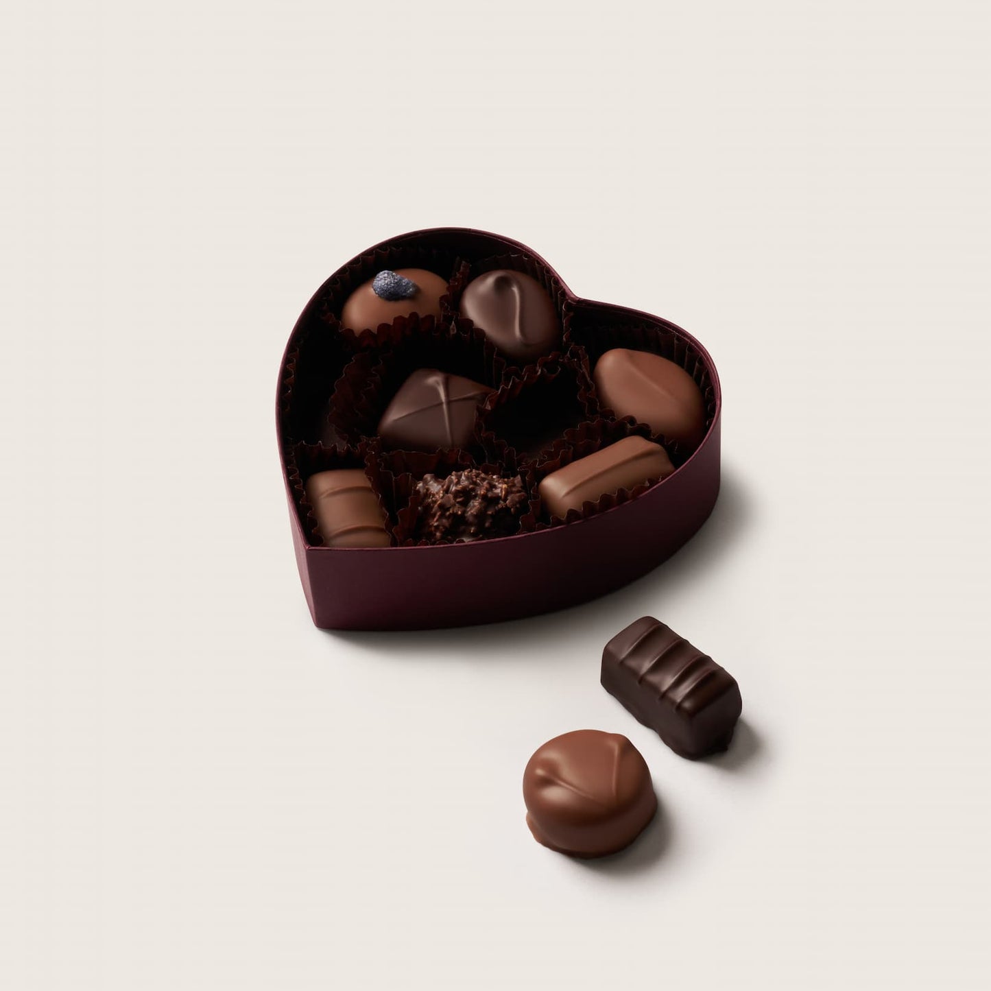 Heart-shaped chocolate box with assorted chocolates on a light background