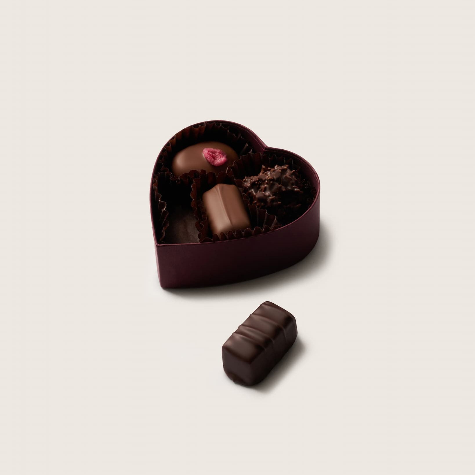 Heart-shaped chocolate box with assorted chocolates on a light background