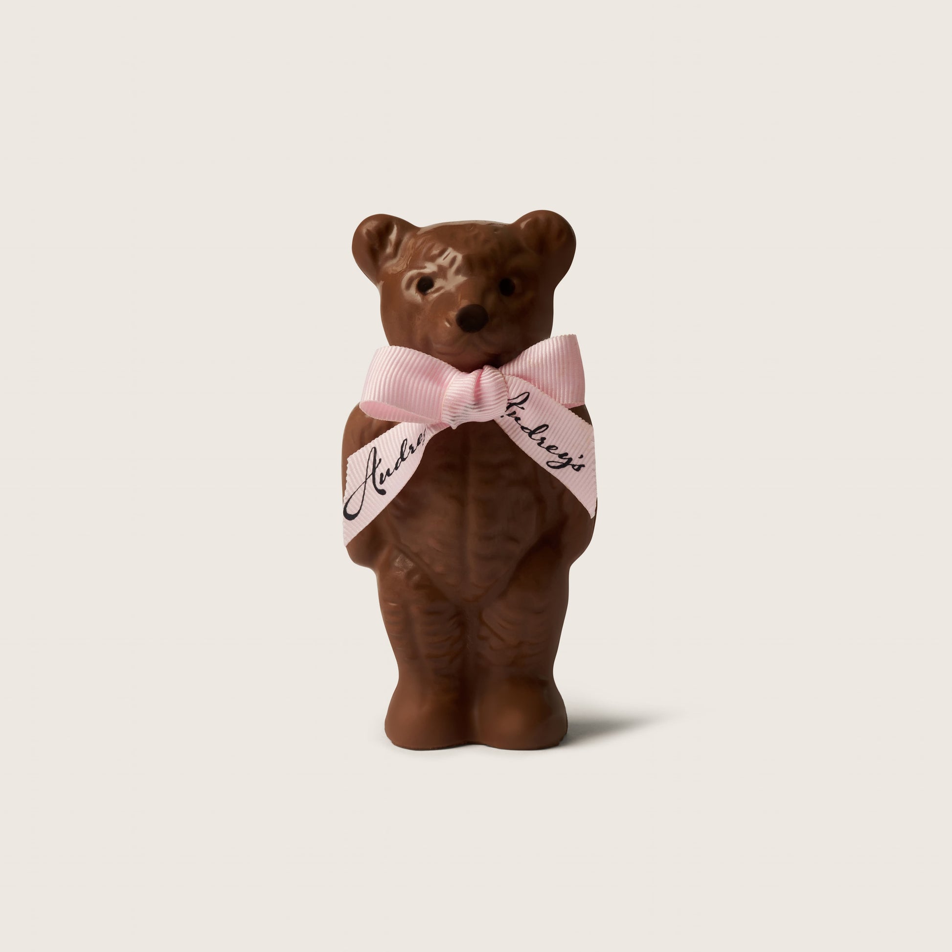 Brown teddy bear wearing a pink bow tie with text on a light beige background