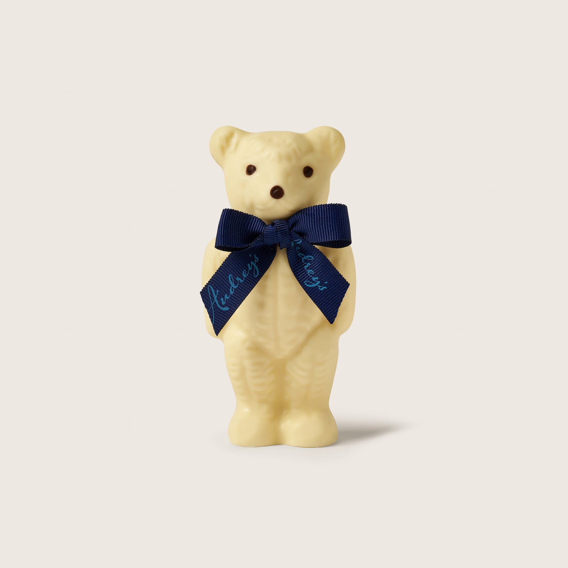 White bear figurine with a blue ribbon on a light beige background