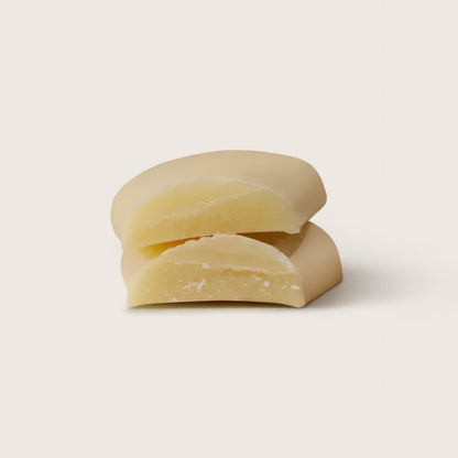 Three pieces of white chocolate stacked on a light beige background