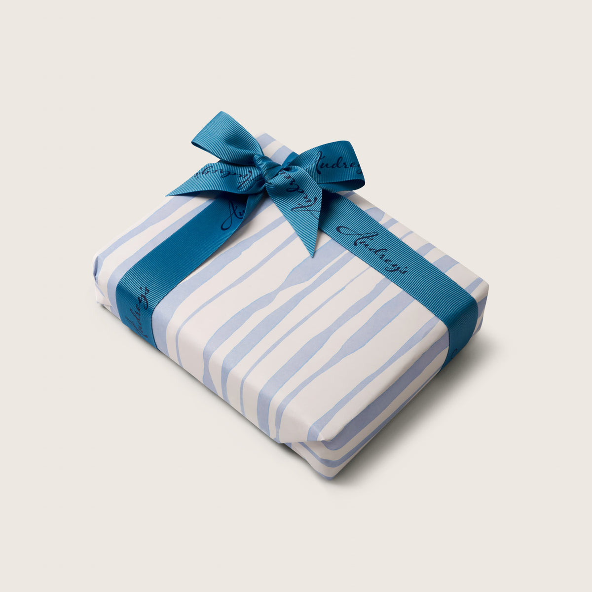 Gift wrapped in blue and white striped paper with a blue ribbon on a light gray background