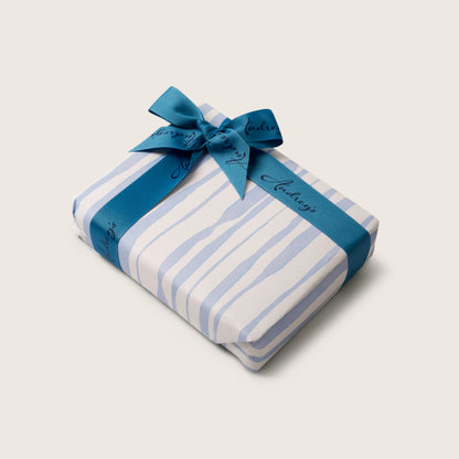 Gift wrapped in blue and white striped paper with a blue ribbon on a light gray background